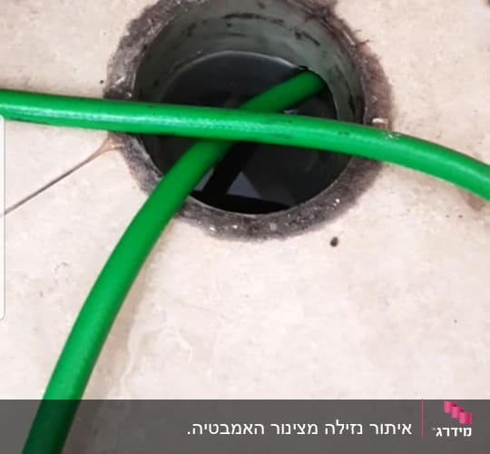 צינור ירוק נכנס לפתח ניקוז ברצפה